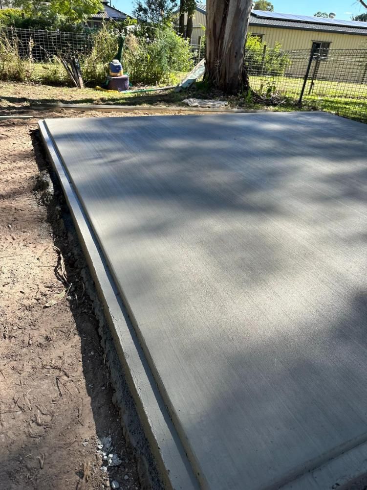 A Concrete Slab Is Sitting On Top Of A Dirt Field Next To A Tree — Burgess Concreting In Kingaroy, QLD