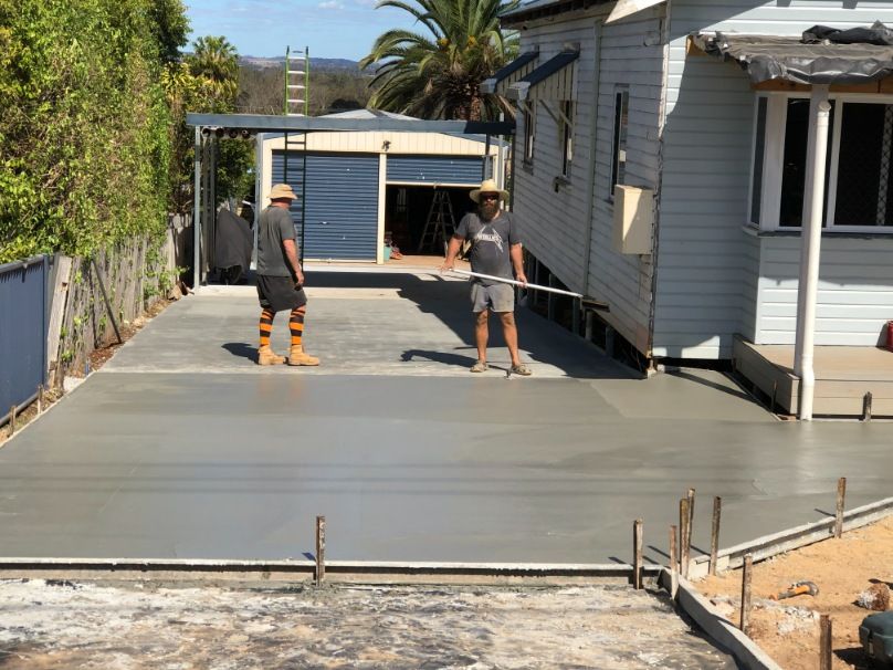 Two Men Are Working on a Concrete Driveway in Front of a House — Burgess Concreting In Proston, QLD