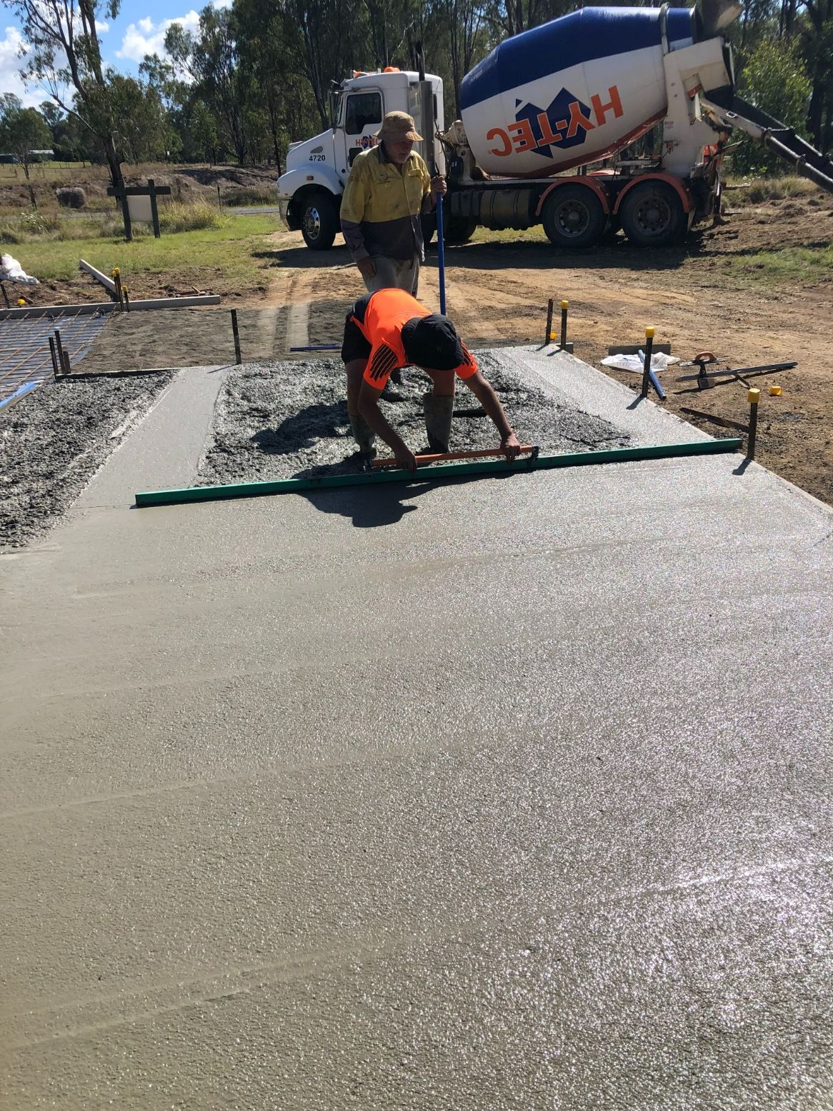 A Man is Laying Concrete in Front of a Cement Truck — Burgess Concreting In Kingaroy, QLD