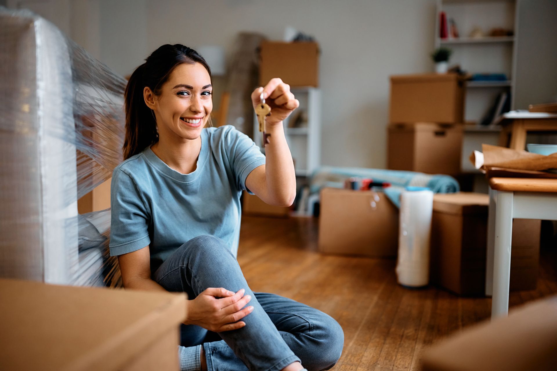 A woman is sitting on the floor in a moving room holding a key.