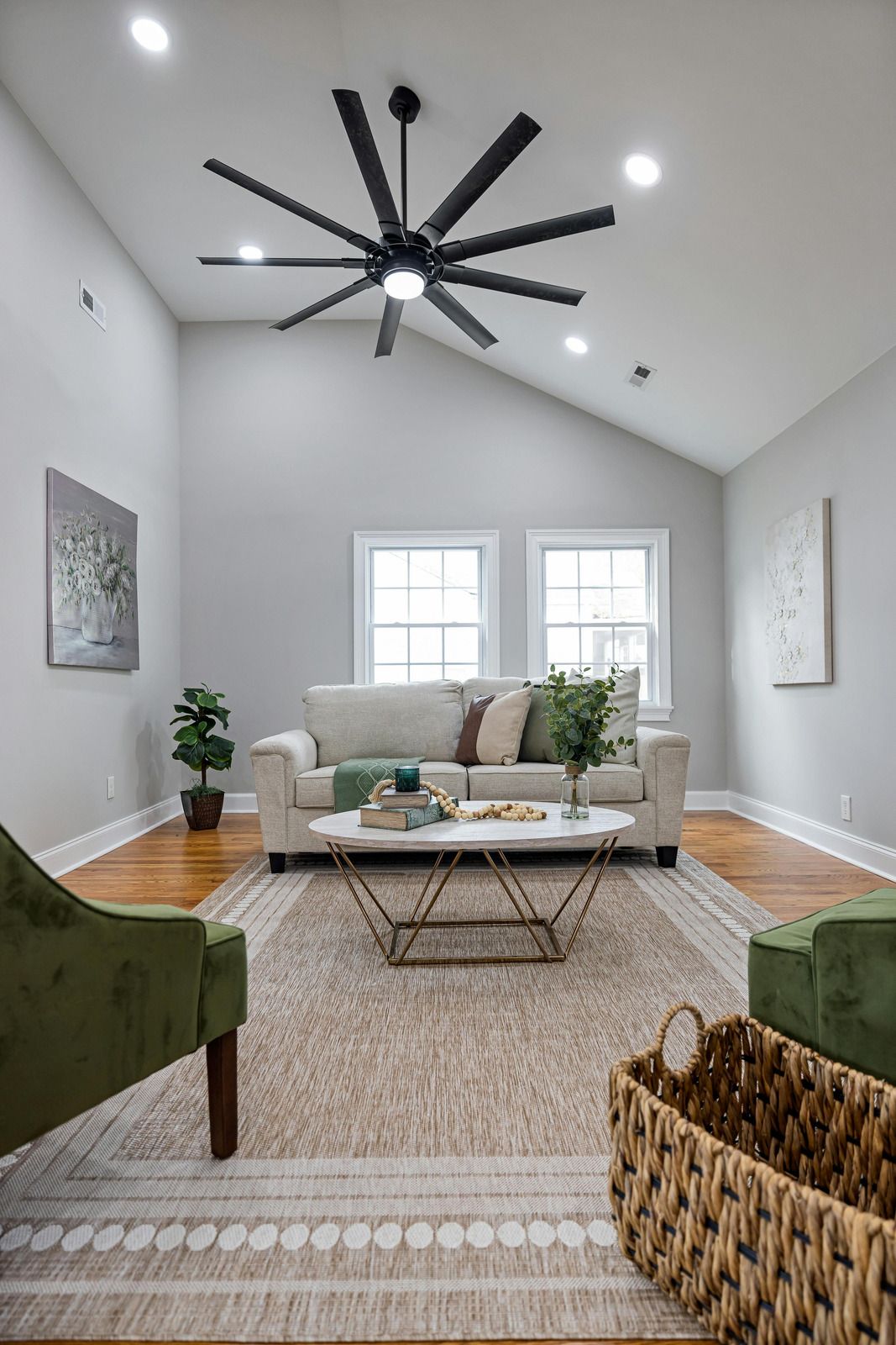 Living room with beige sofa, green chairs, and large black ceiling fan.