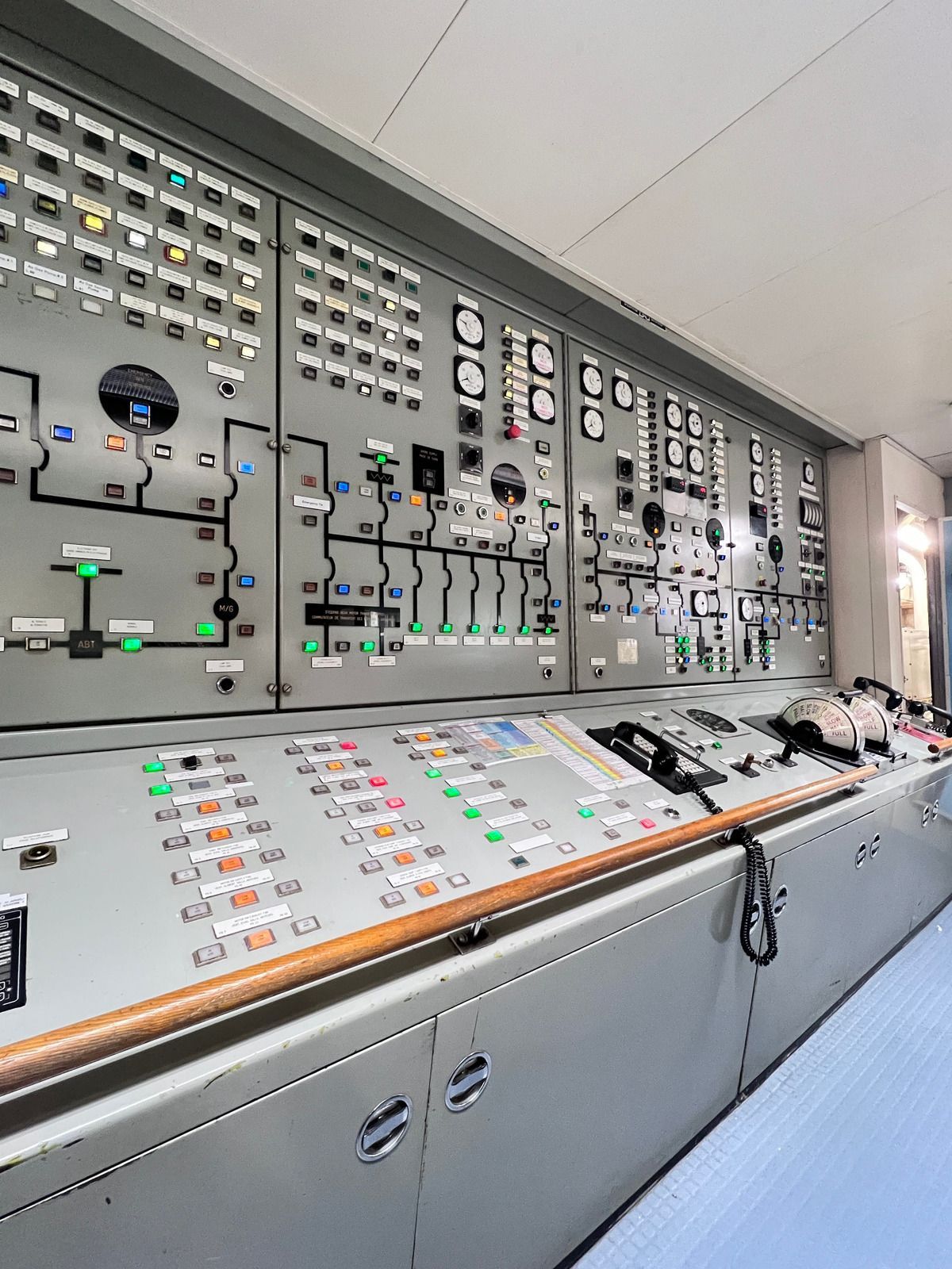 Control panel room with numerous buttons, gauges, and switches, likely for a ship or industrial plant.