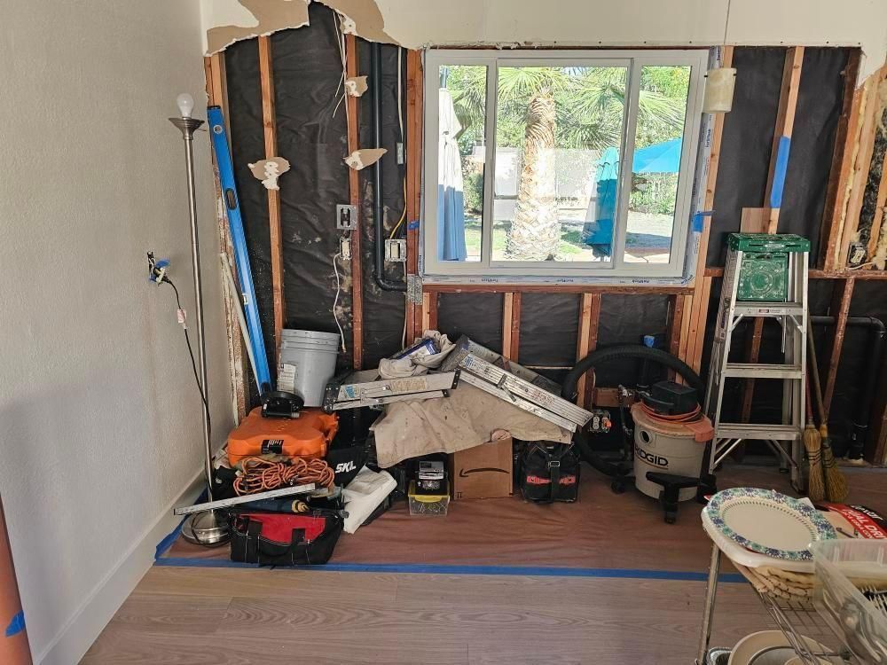 Room under construction with exposed framing, window, and scattered tools.