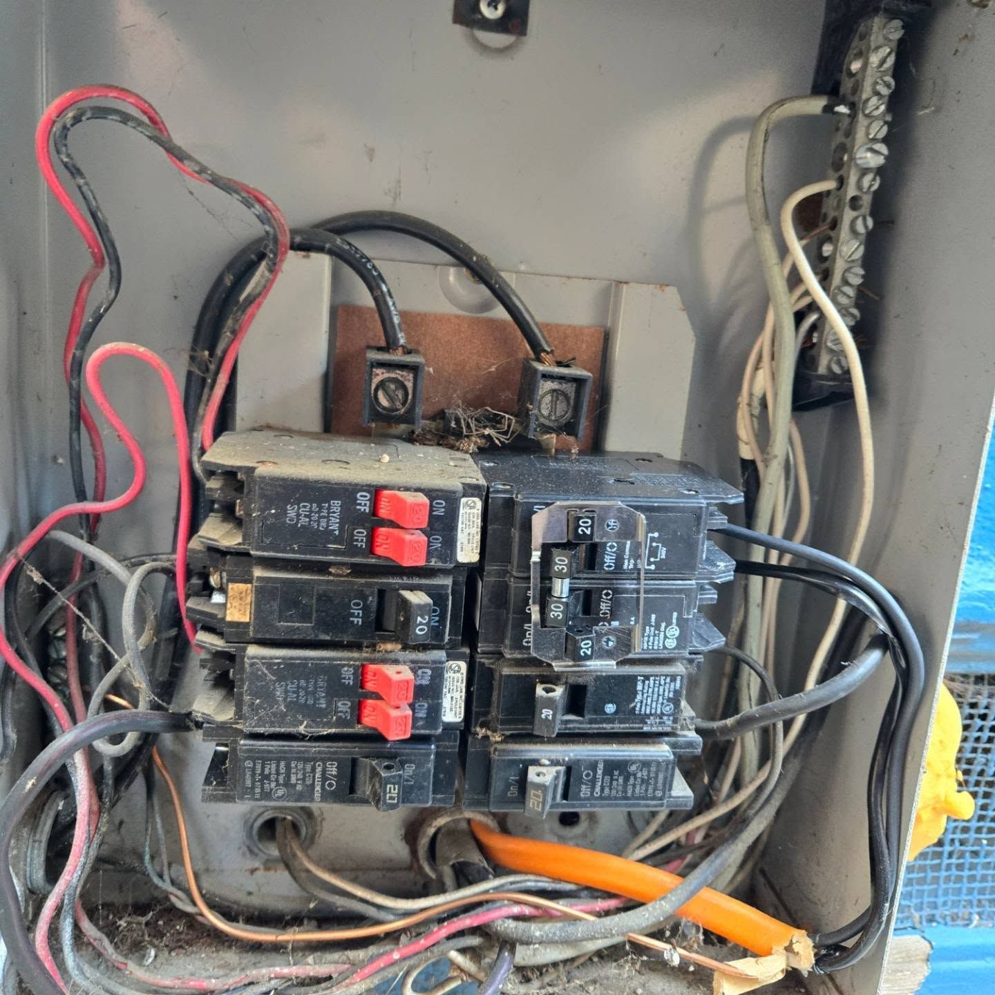 Open electrical panel with circuit breakers and wiring. Some wires appear frayed.