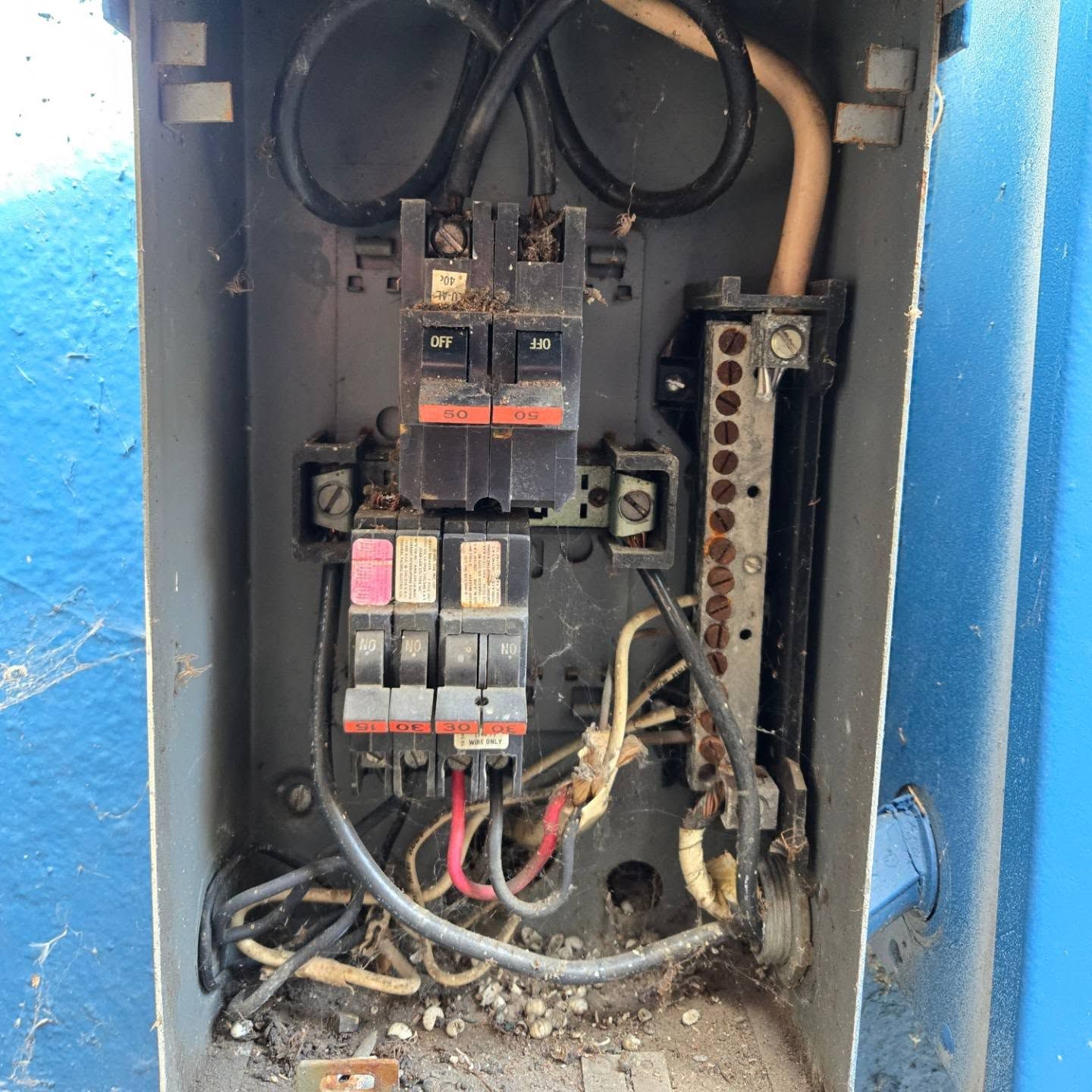 Open electrical panel with circuit breakers, wires, and grounding bar.