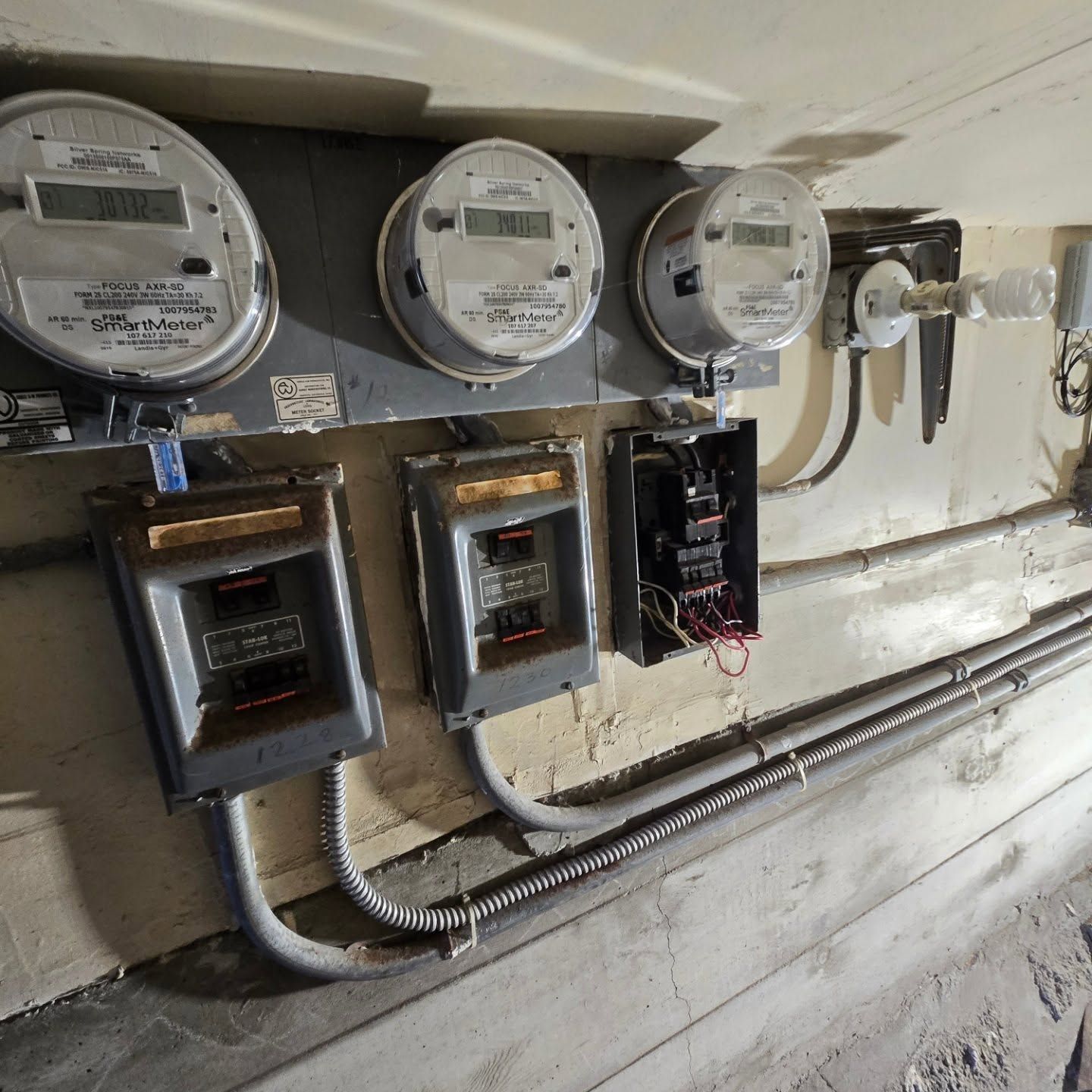 Electrical meters and breaker boxes mounted on a wall.