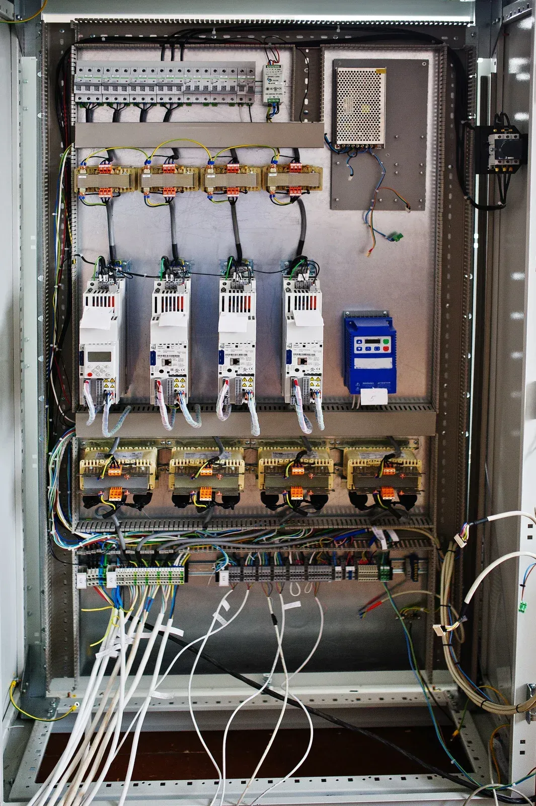 Electrical control panel with wires, circuit breakers, and components inside a metal cabinet.