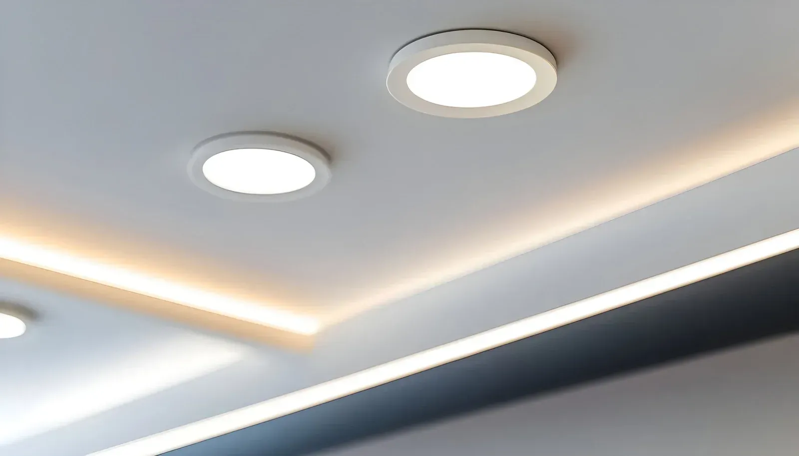 Two white recessed ceiling lights and recessed lighting along a ceiling edge.