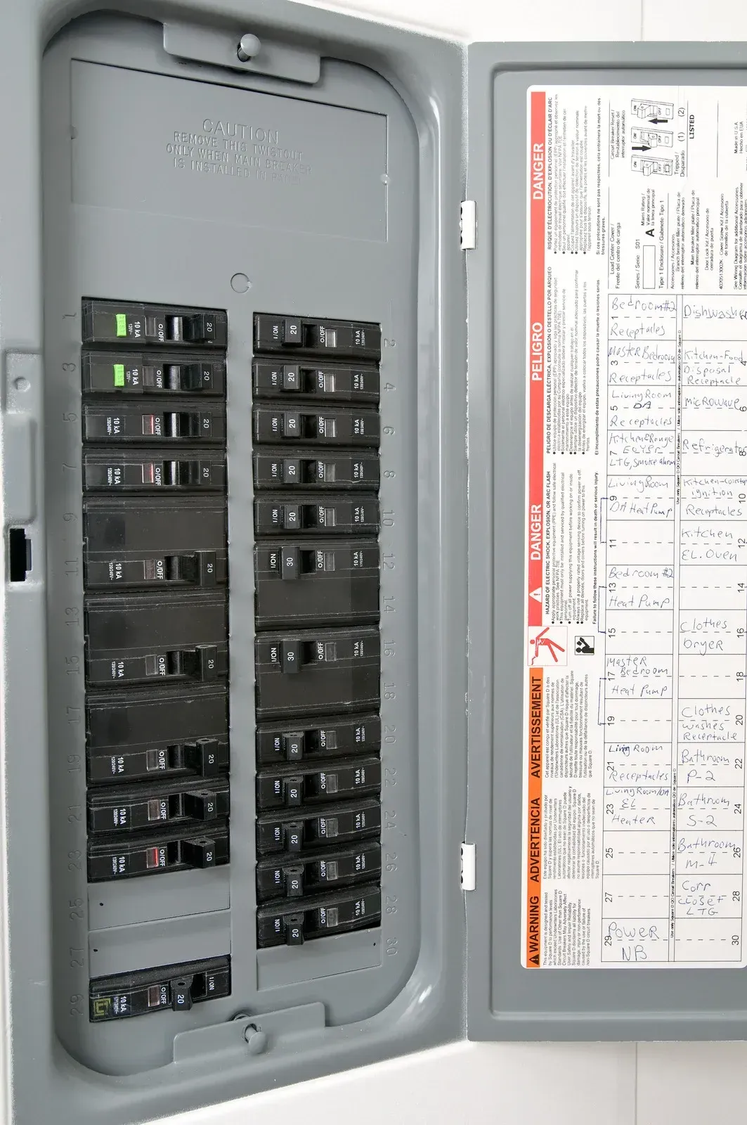 An open, gray electrical panel with various circuit breakers. A green light is on at the top.