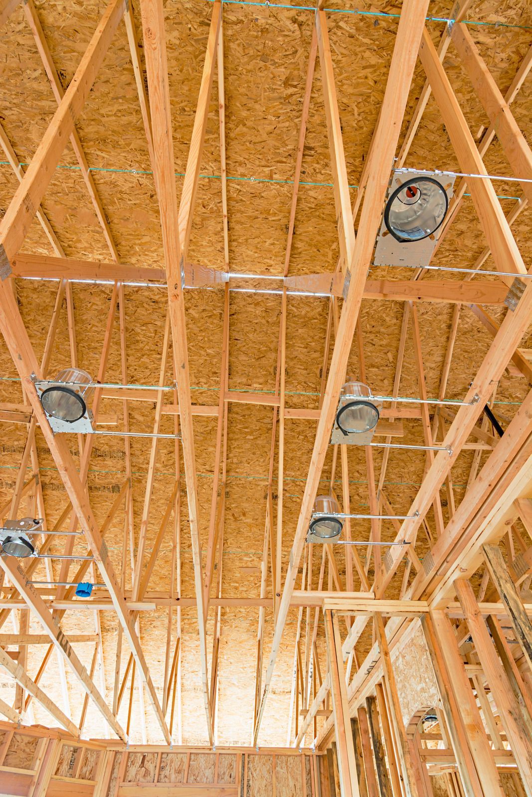Wooden framework of a building's ceiling, with recessed lighting fixtures installed.