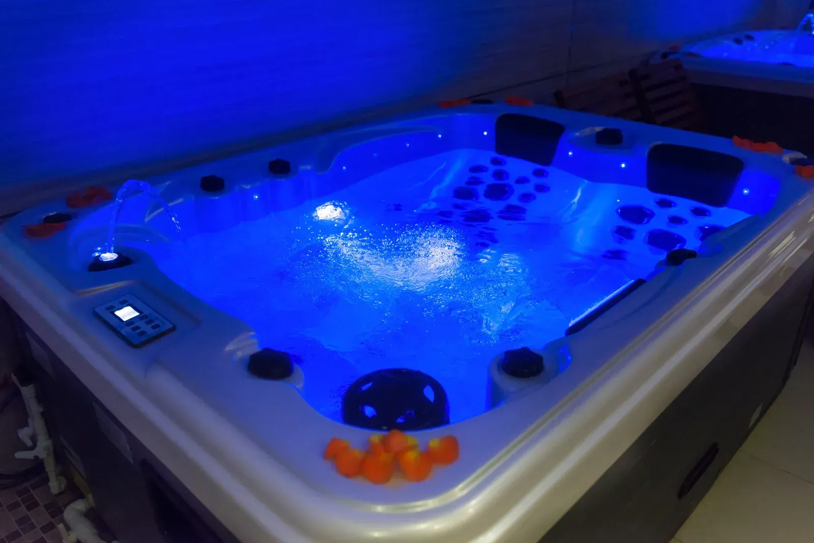 Lit-up blue hot tub with bubbles and jets; interior setting.