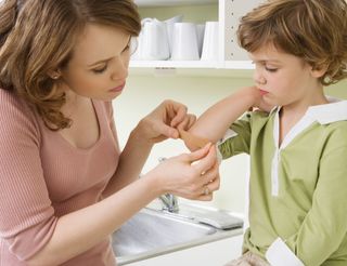 Mother putting plaster on boy