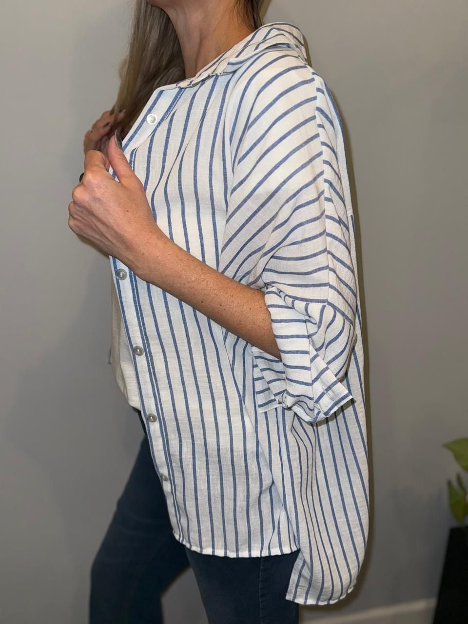 Mujer que lleva una camisa abotonada a rayas sobre una camiseta de Boston 1981 y jeans azules.