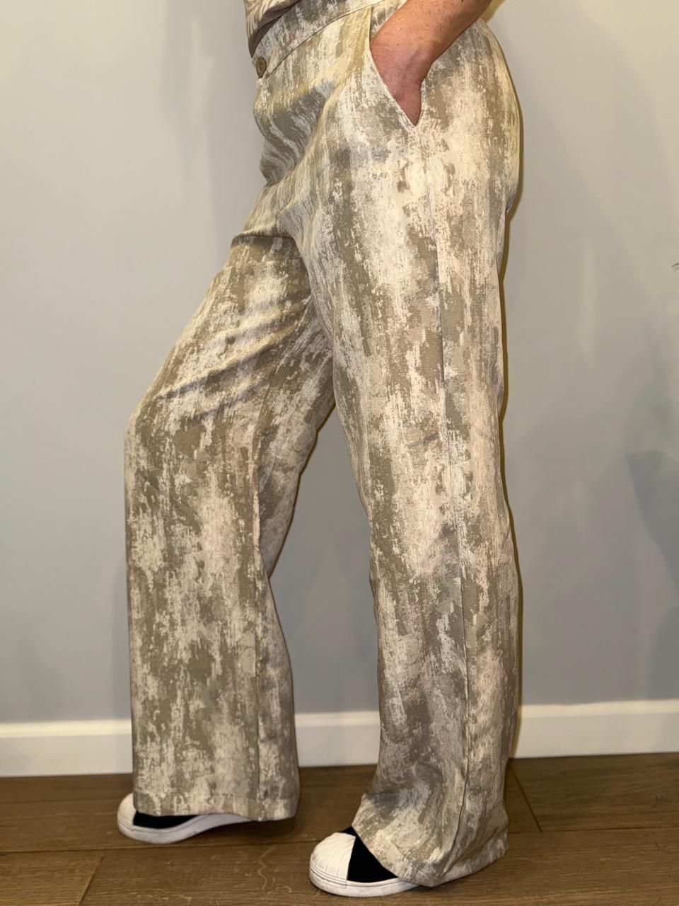 Persona con pantalones estampados, con la mano en el bolsillo, de pie en el interior.