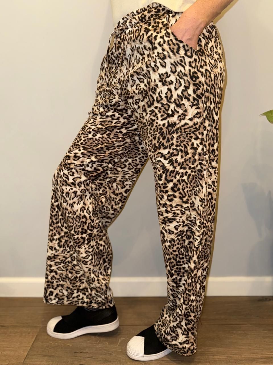 Persona que viste pantalones con estampado de guepardo, con una mano en el bolsillo y zapatos negros.
