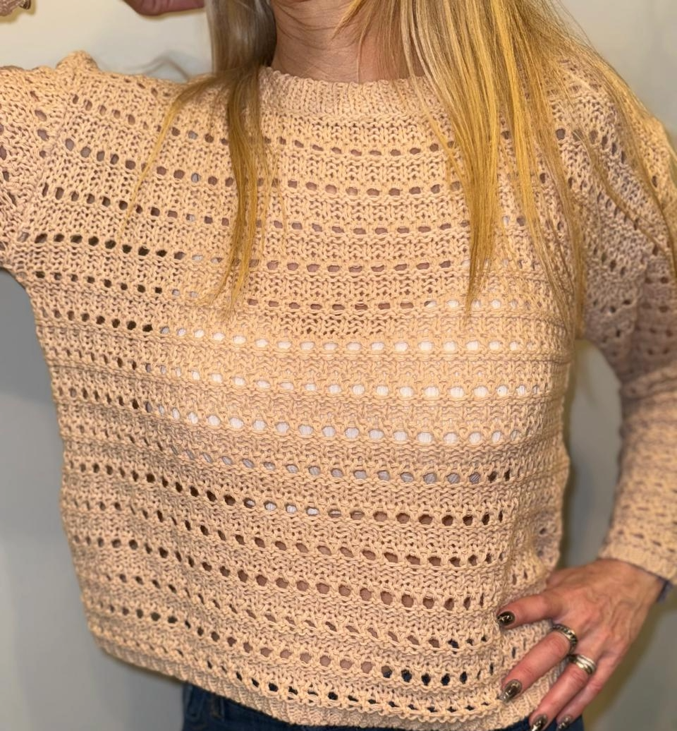 Mujer con un suéter de punto color melocotón. Corto, con detalles de punto calados.