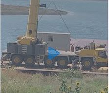 A large crane is lifting a building into the water.