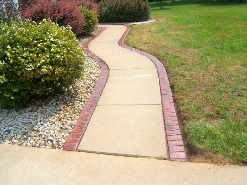 A concrete walkway with a red brick border