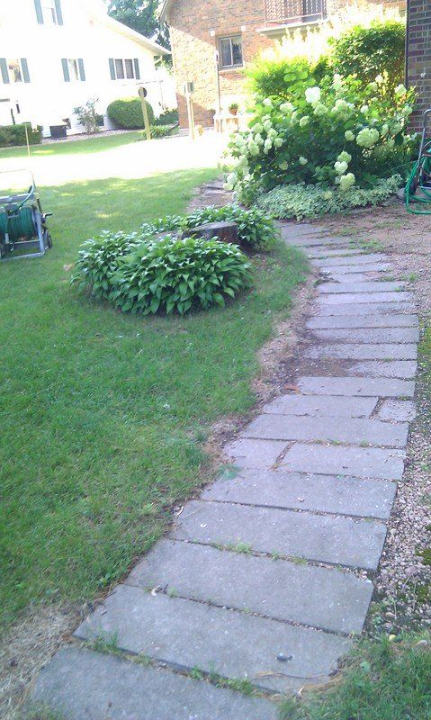 A stone walkway leading to a house in a yard.