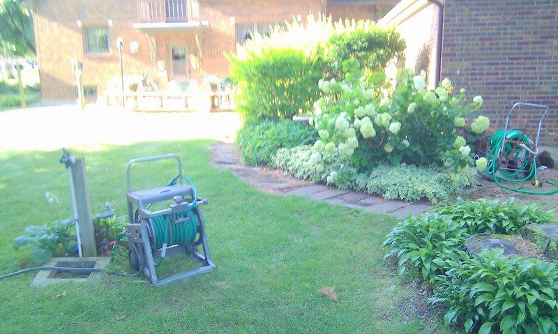 A hose reel is sitting in the middle of a lush green yard.