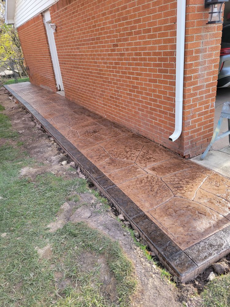 A sidewalk is being built in front of a brick house.