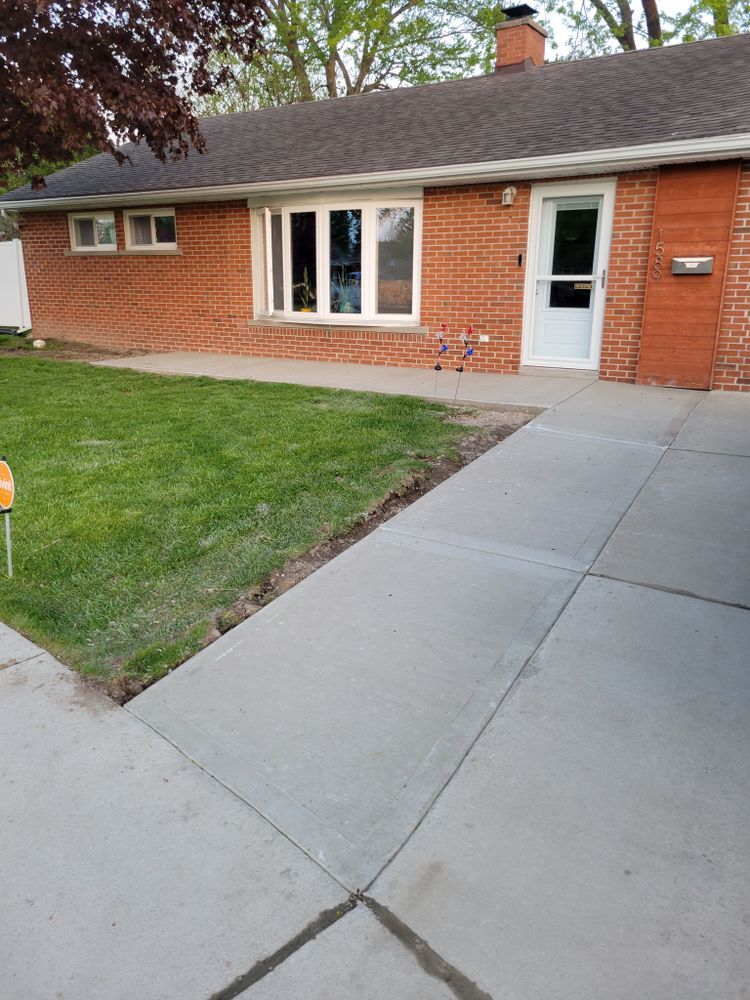 A brick house with a concrete walkway leading to it.
