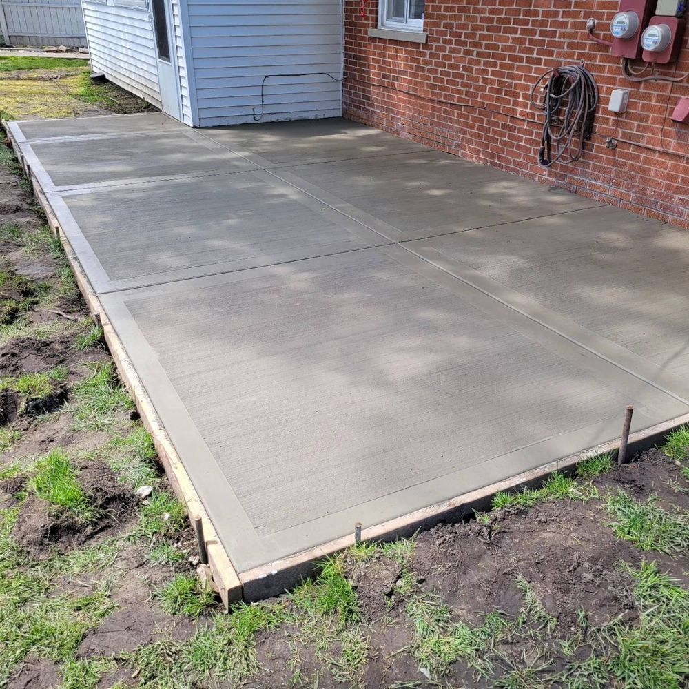 A concrete patio is being built in front of a brick house.