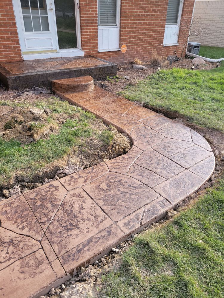 A concrete walkway is being built in front of a brick house.