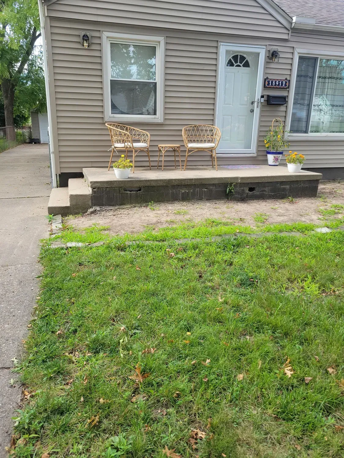 A small house with a porch and chairs in front of it.