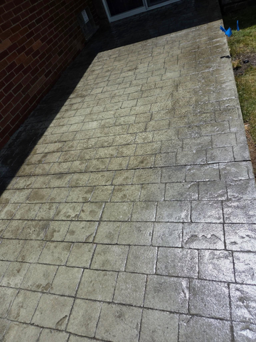 A dirty concrete walkway next to a brick building.