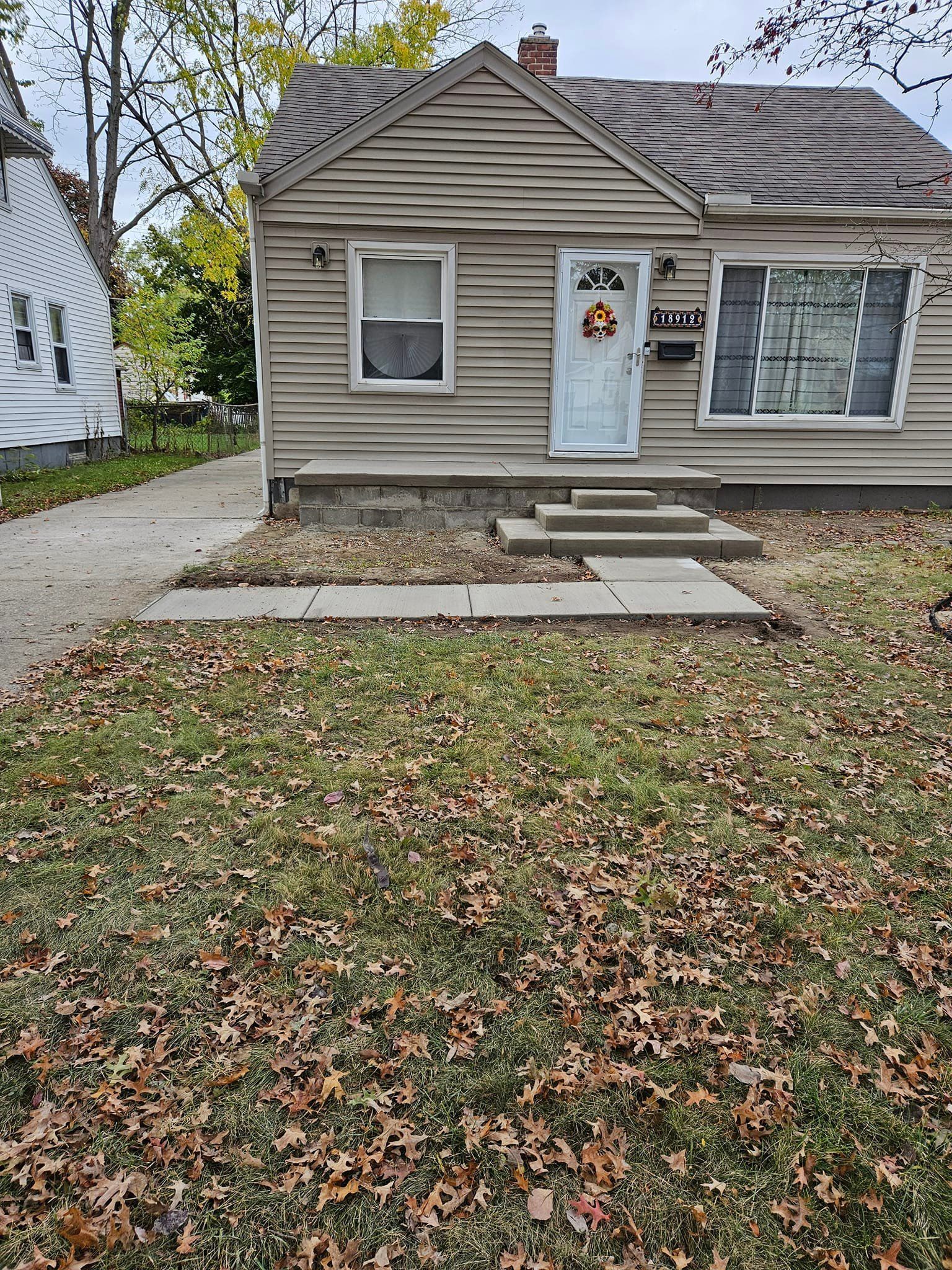 A small house with a lot of leaves on the ground in front of it.