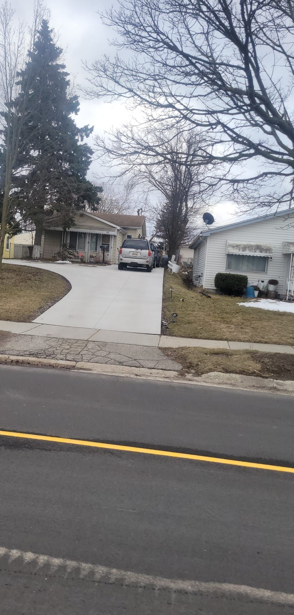 A couple of cars are parked in a driveway next to a house.