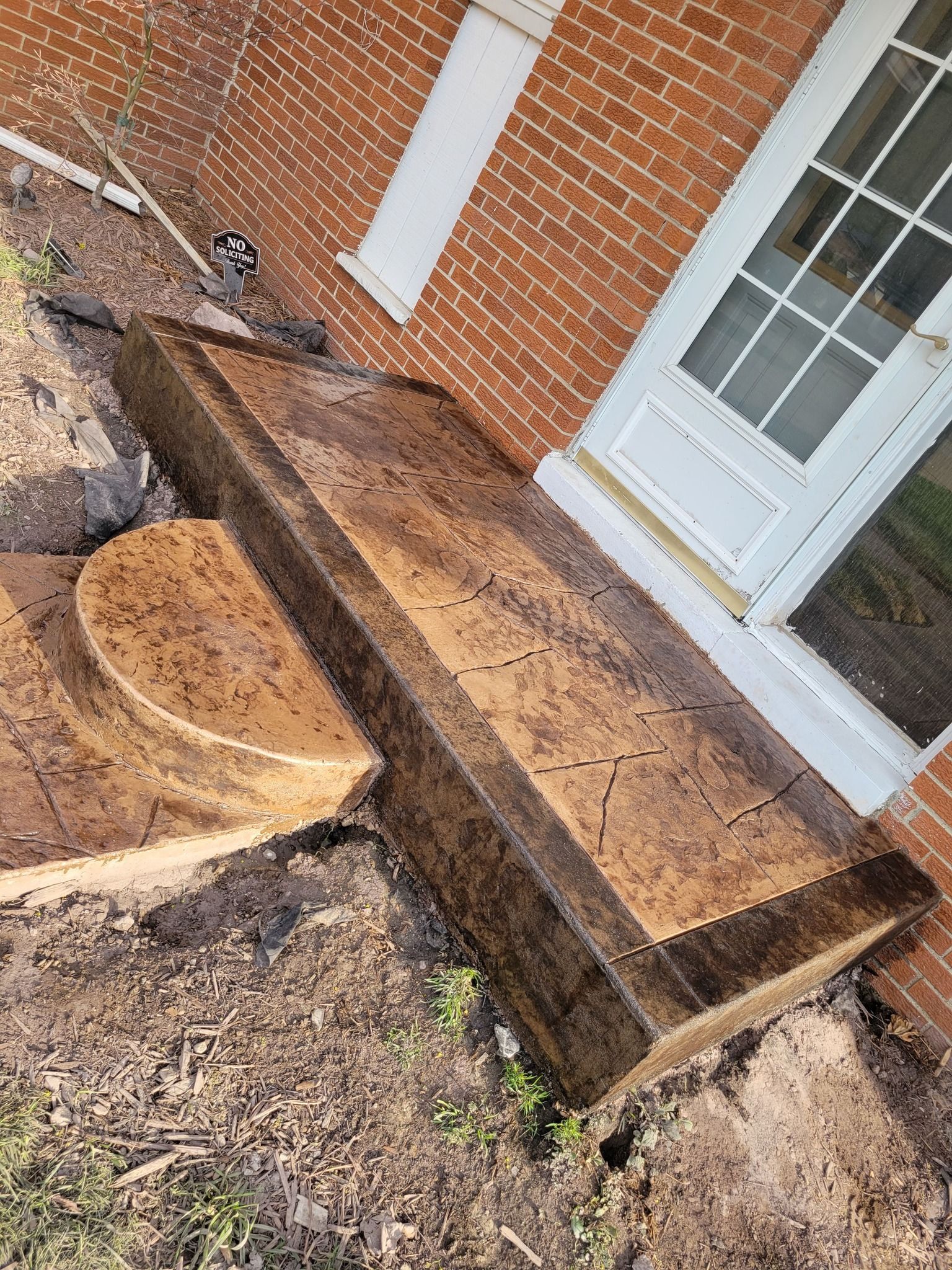 A wooden bench is sitting in front of a brick building.