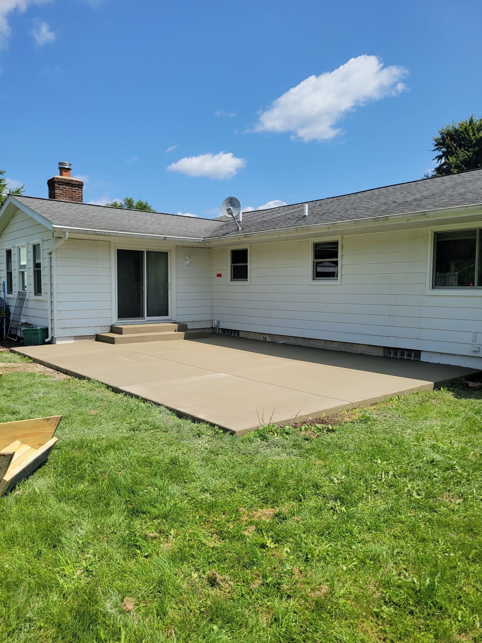 A white house with a concrete patio in the backyard.