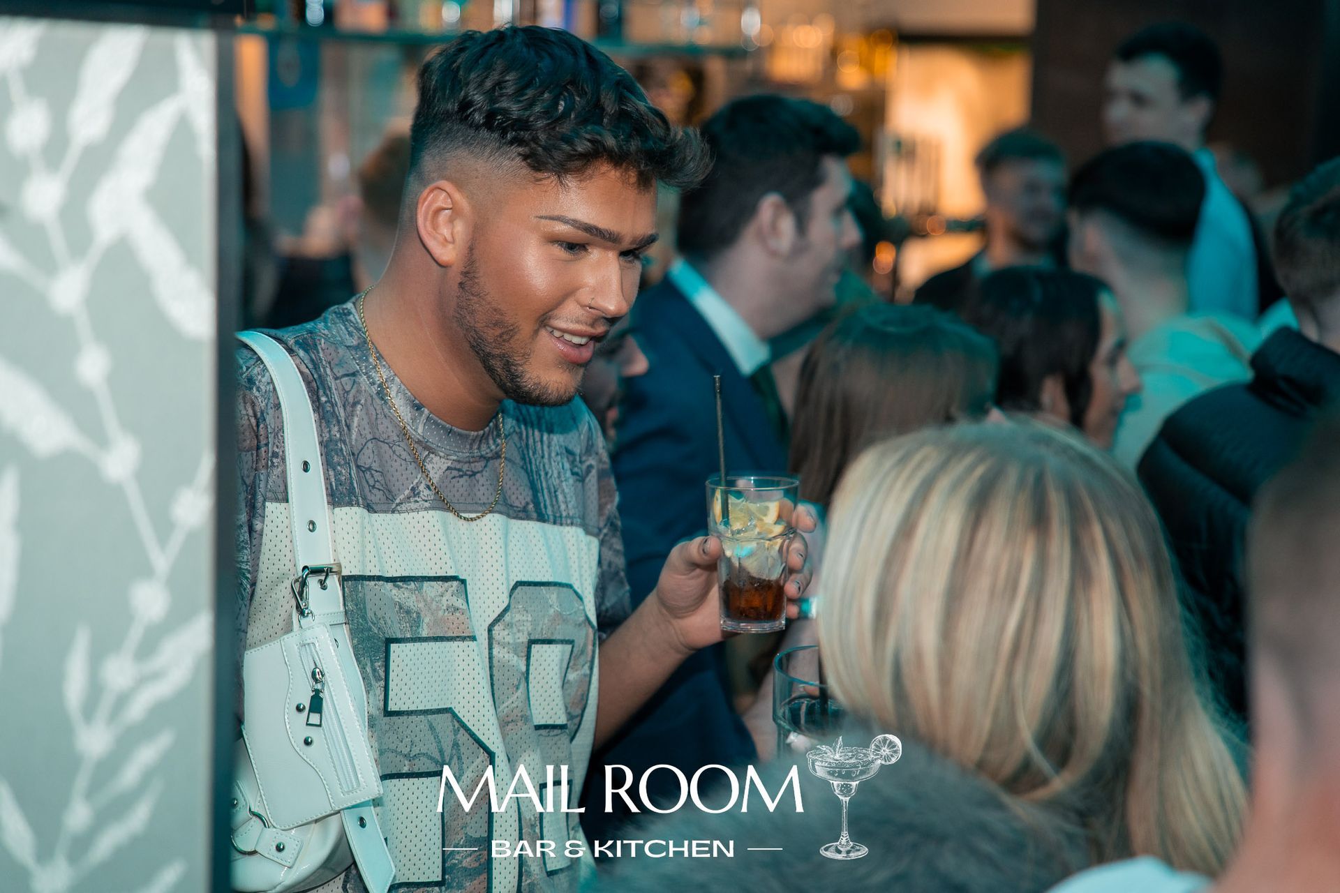 A man is holding a drink in front of a woman at a party.
