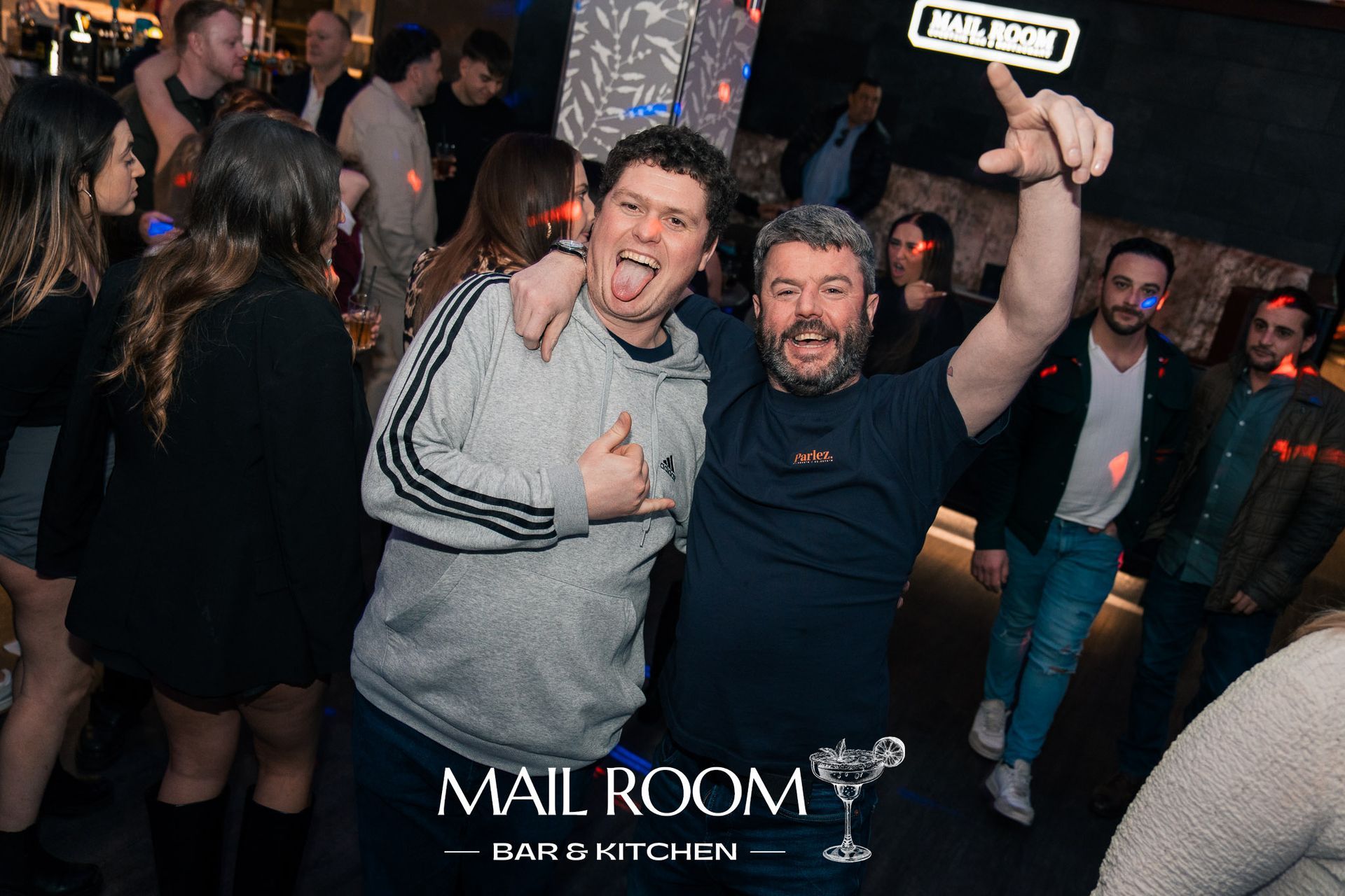 Two men are standing next to each other in a crowd at a party.