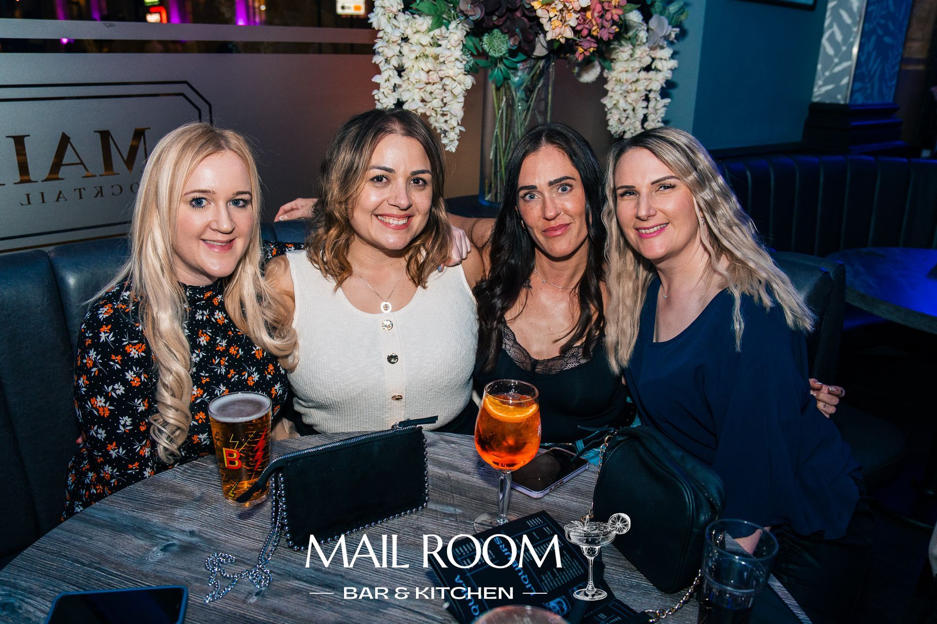 A group of women are posing for a picture at a table in a restaurant.