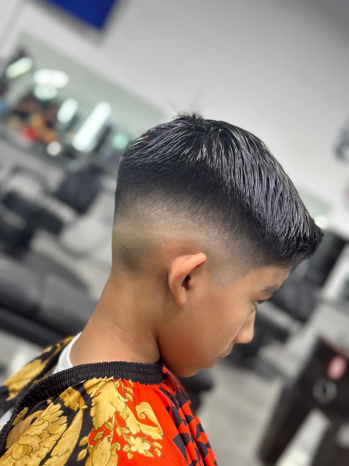 Boy with a fade haircut, side profile, in a barber shop.
