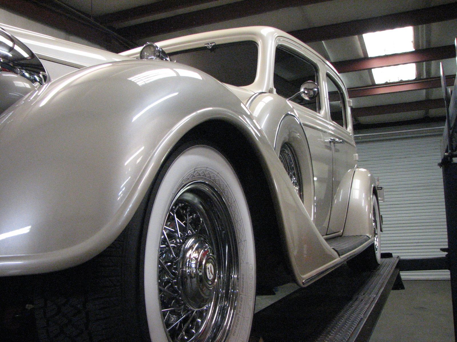 Silver classic car parked indoors in a garage, shown from a low front-side angle