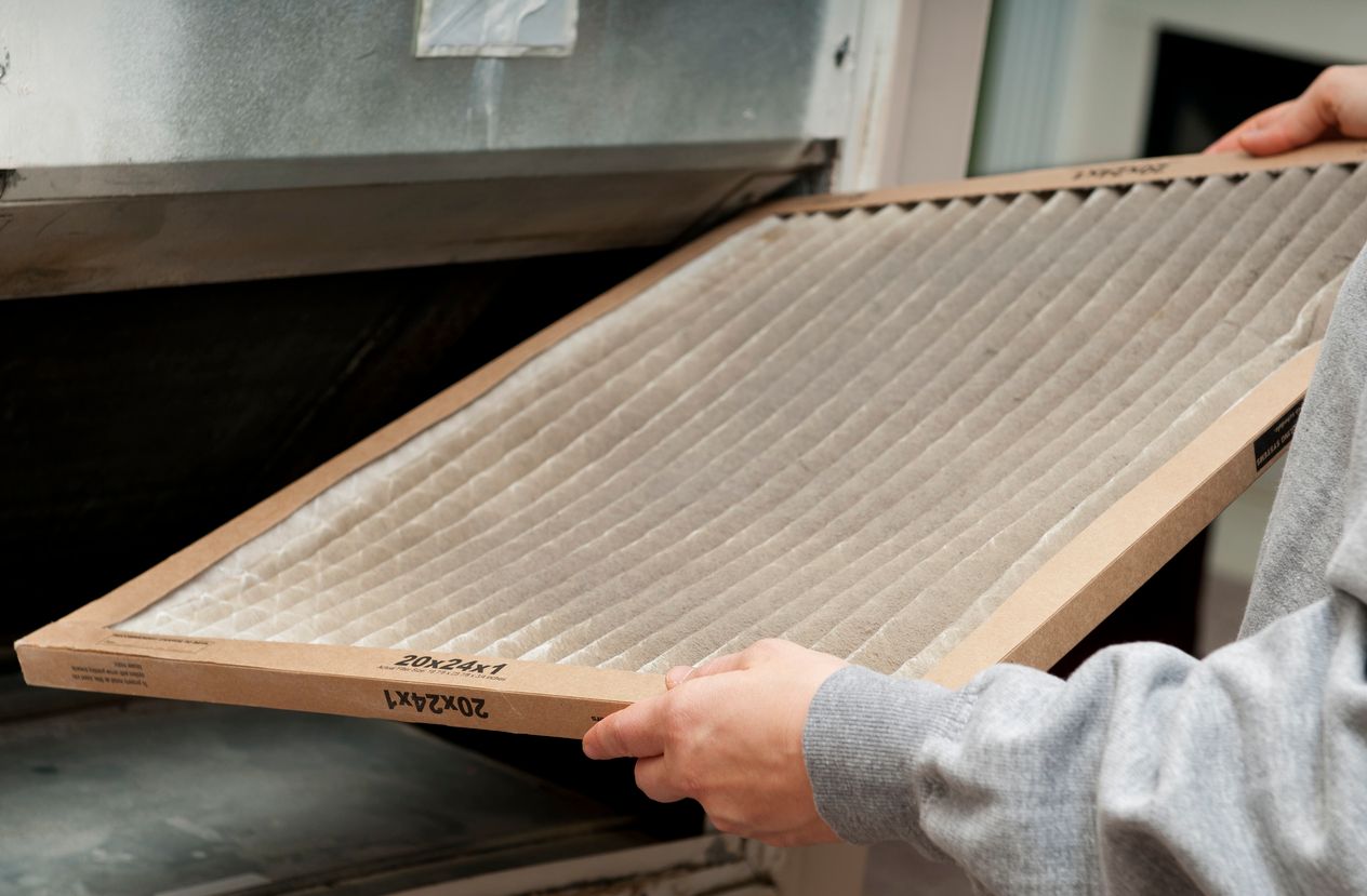 An HVAC technician holding a dirty air filter, ready to be replaced