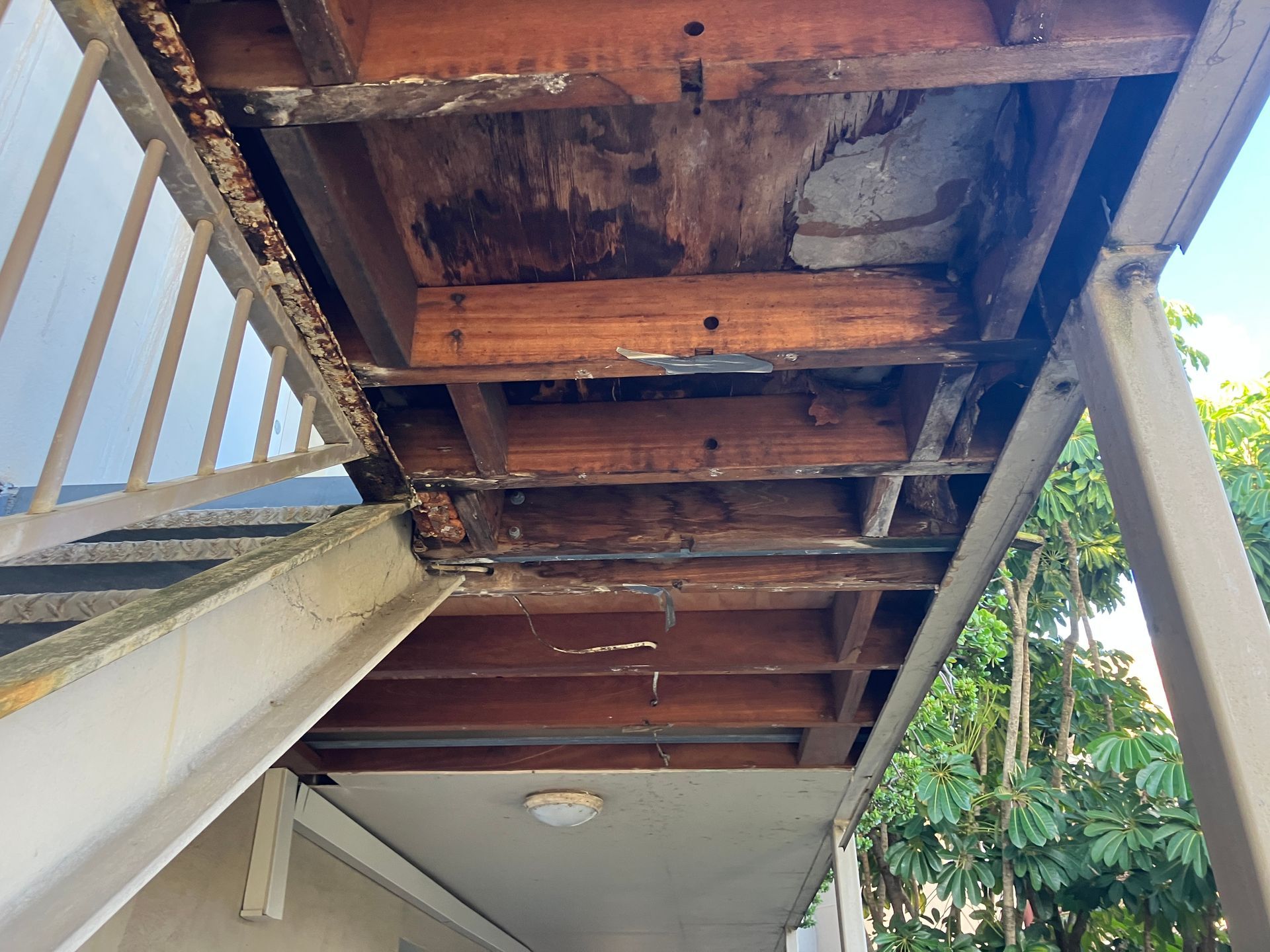 Underside of a wooden deck showing significant water damage and deterioration.