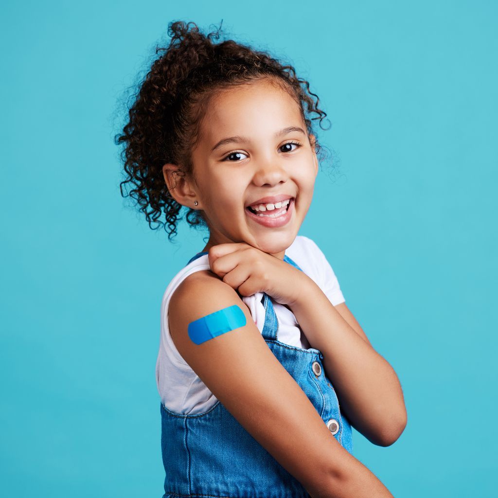 young girl with a bright blue bandage on her arm after getting a vaccine