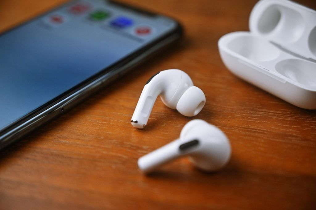 Photo of airpods on table with cellphone and case.