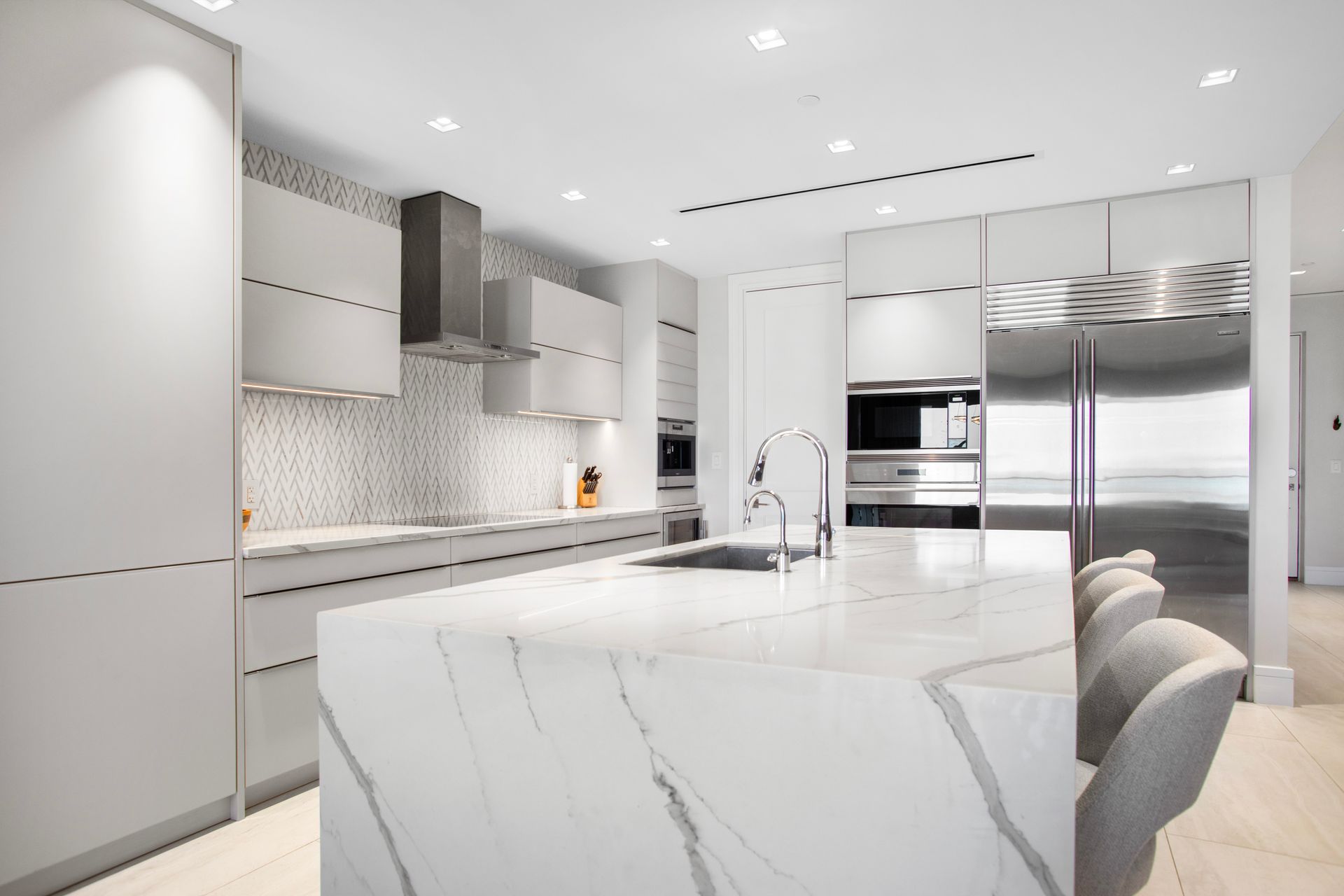 A kitchen with white cabinets and stainless steel appliances in the luxury properties of Bond Vacations Bahamas