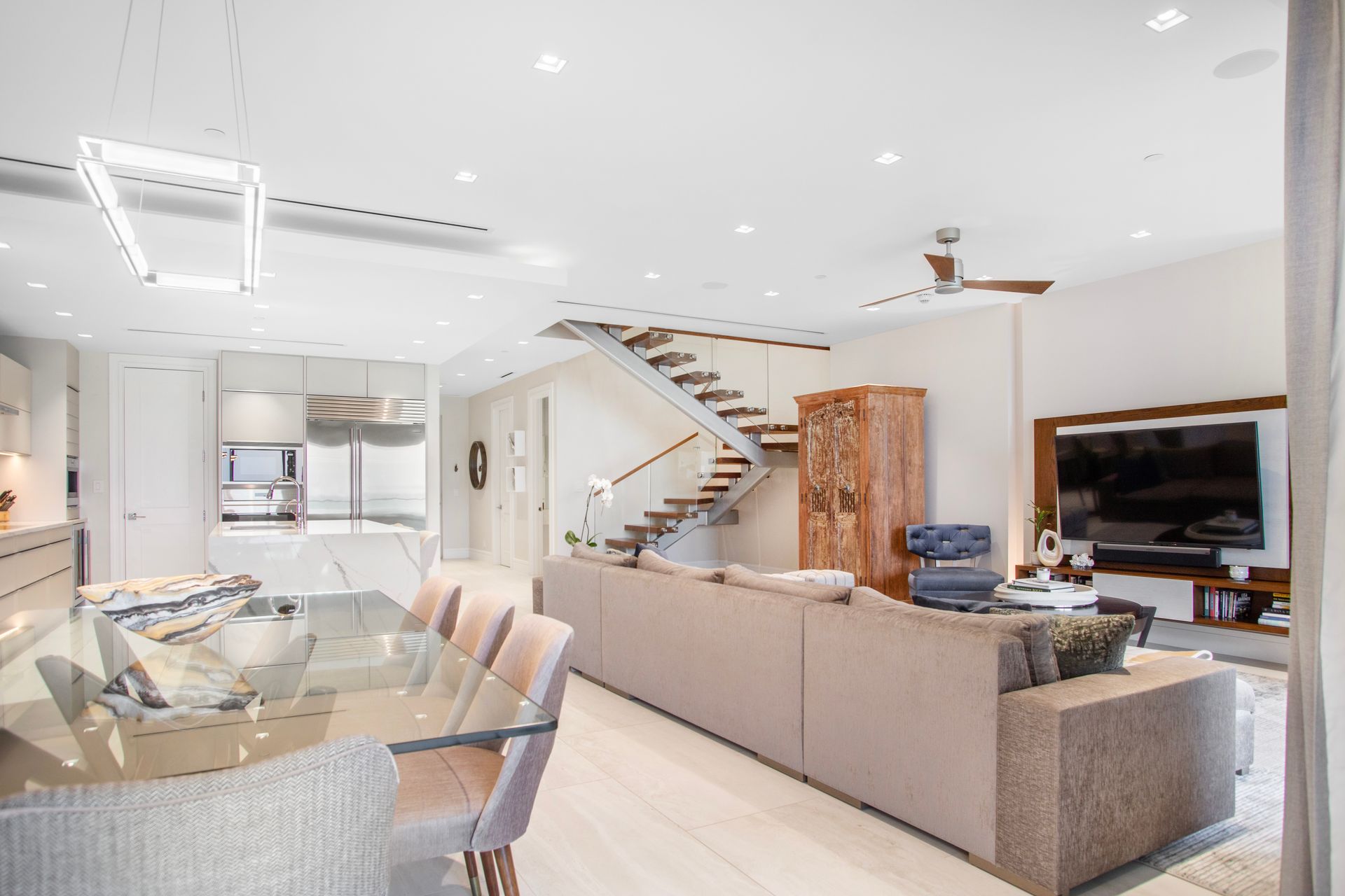 A spacious living room with a couch, table, chairs and stairs in one cable beach Nassau Bahamas