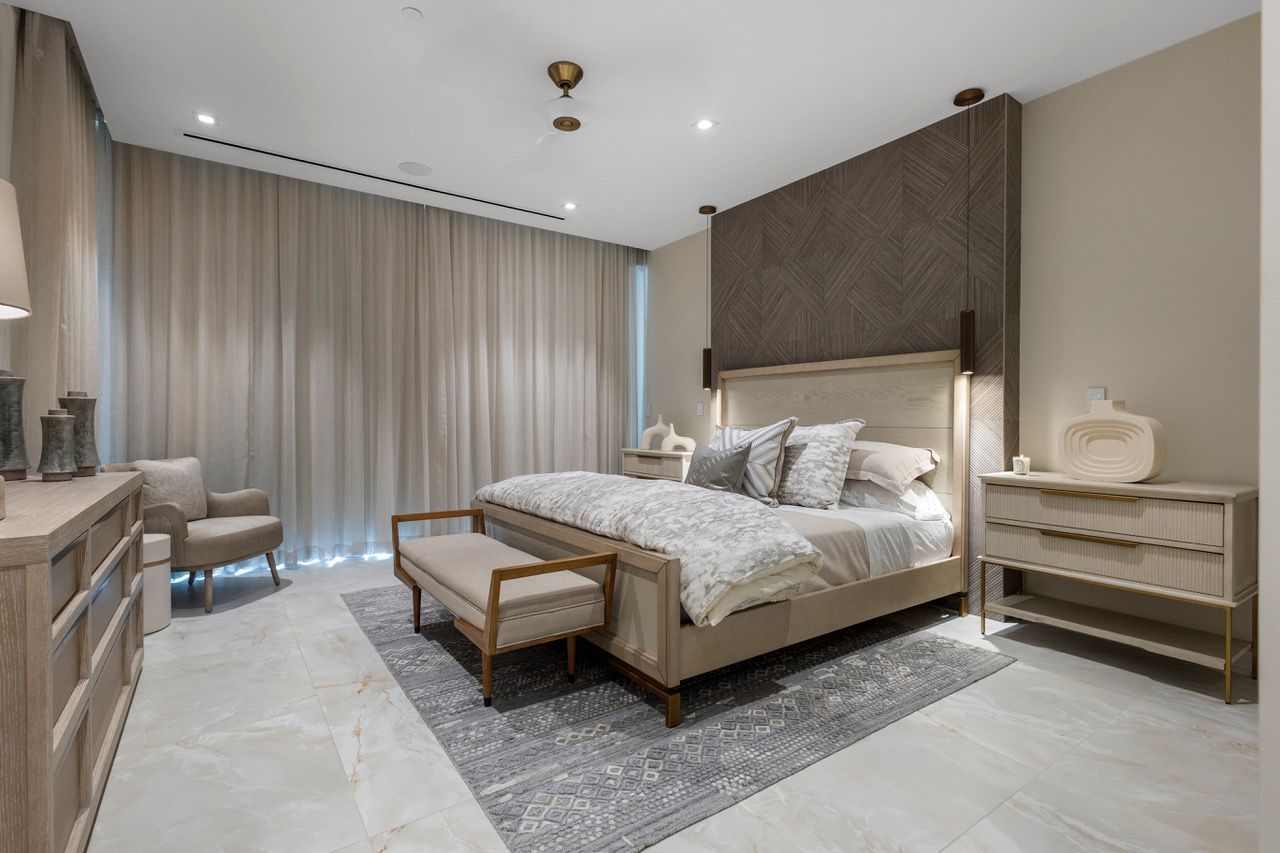 A master bedroom with a large bed , dresser , chair and nightstand in Bond Vacations properties Nassau Bahamas