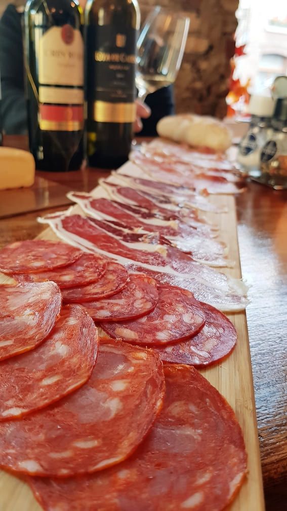 a wooden cutting board topped with sliced meat and wine bottles .