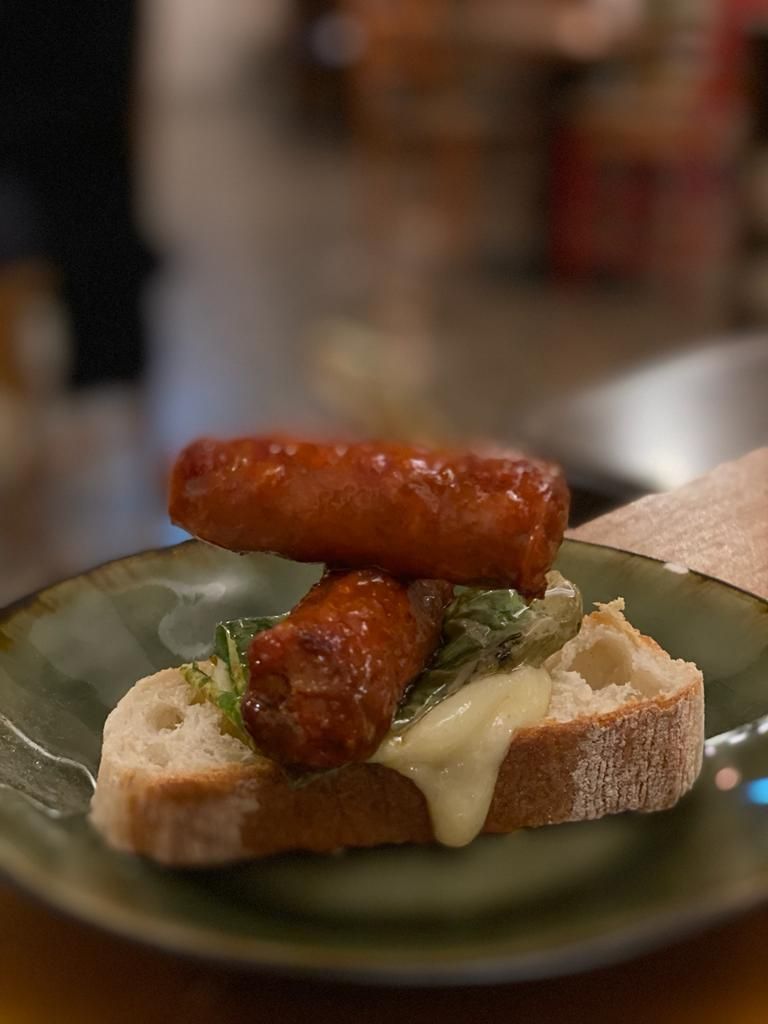 a plate of food with two sausages on top of a piece of bread .