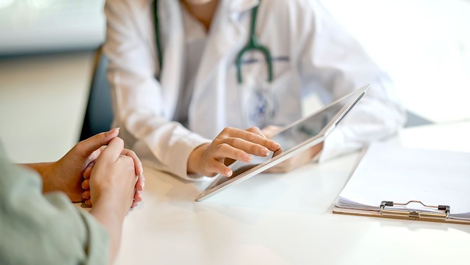 a doctor is talking to a patient while looking at a tablet .