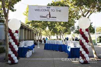 Entrance to the Yorba Linda Orange County Experience event with balloon columns, tables with items, and a welcome banner.